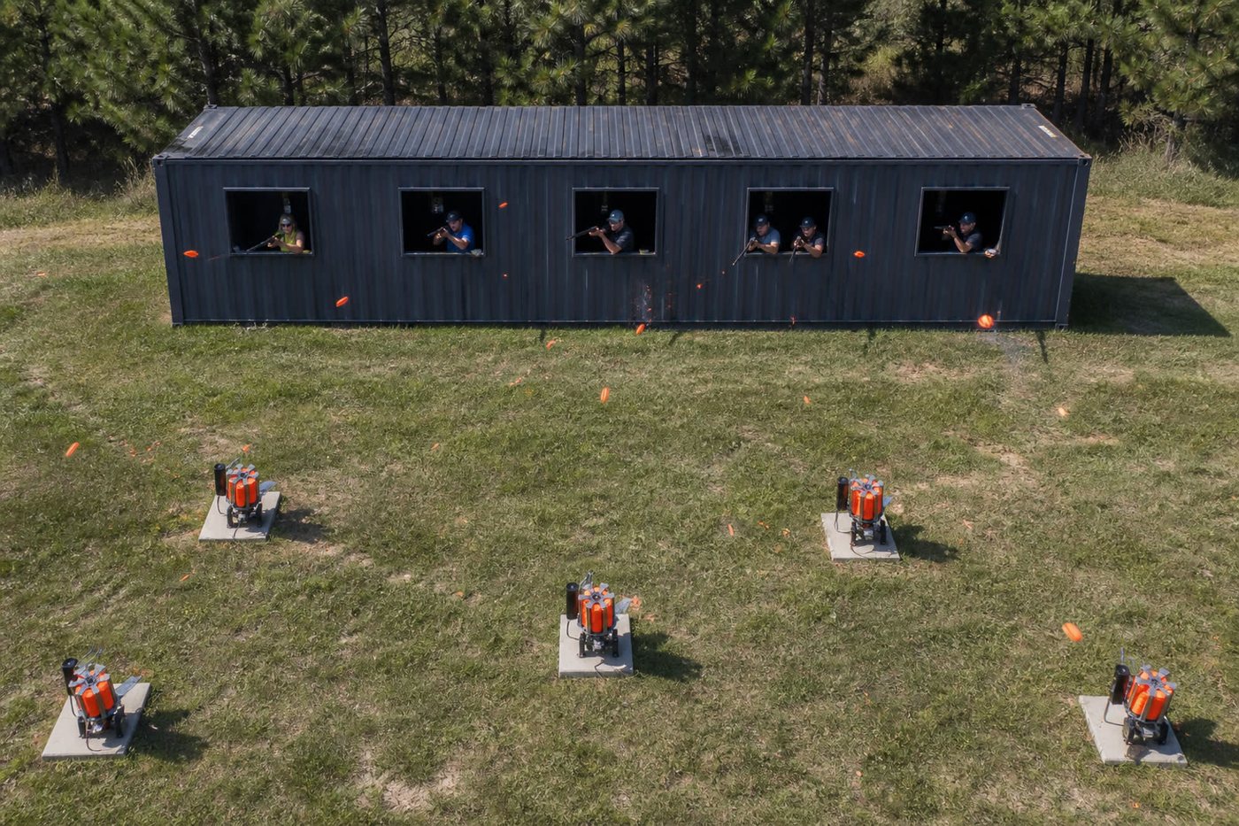 Aerial of the metal shipping container with five shooting windows, clay machines on the field, and orange targets in the air
