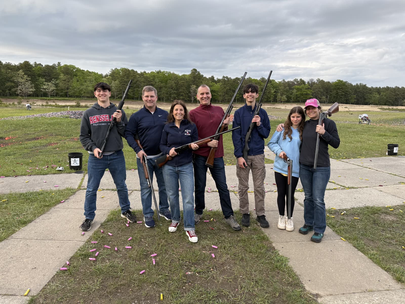 A mixed group of seven smiling with shotguns after a round