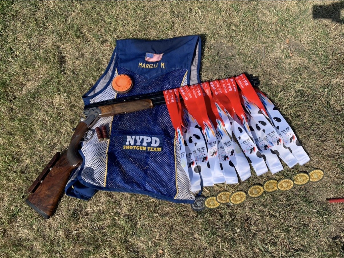 Mike Marelli’s NYPD Shotgun Team vest with an over-under shotgun and 2019 World Games medals on the grass