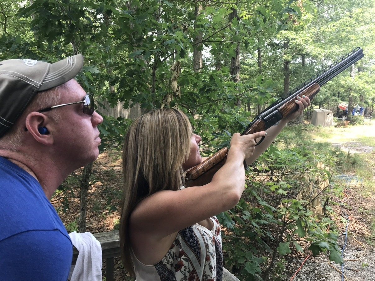 Mike Marelli coaching a student aiming an over-under shotgun on the field