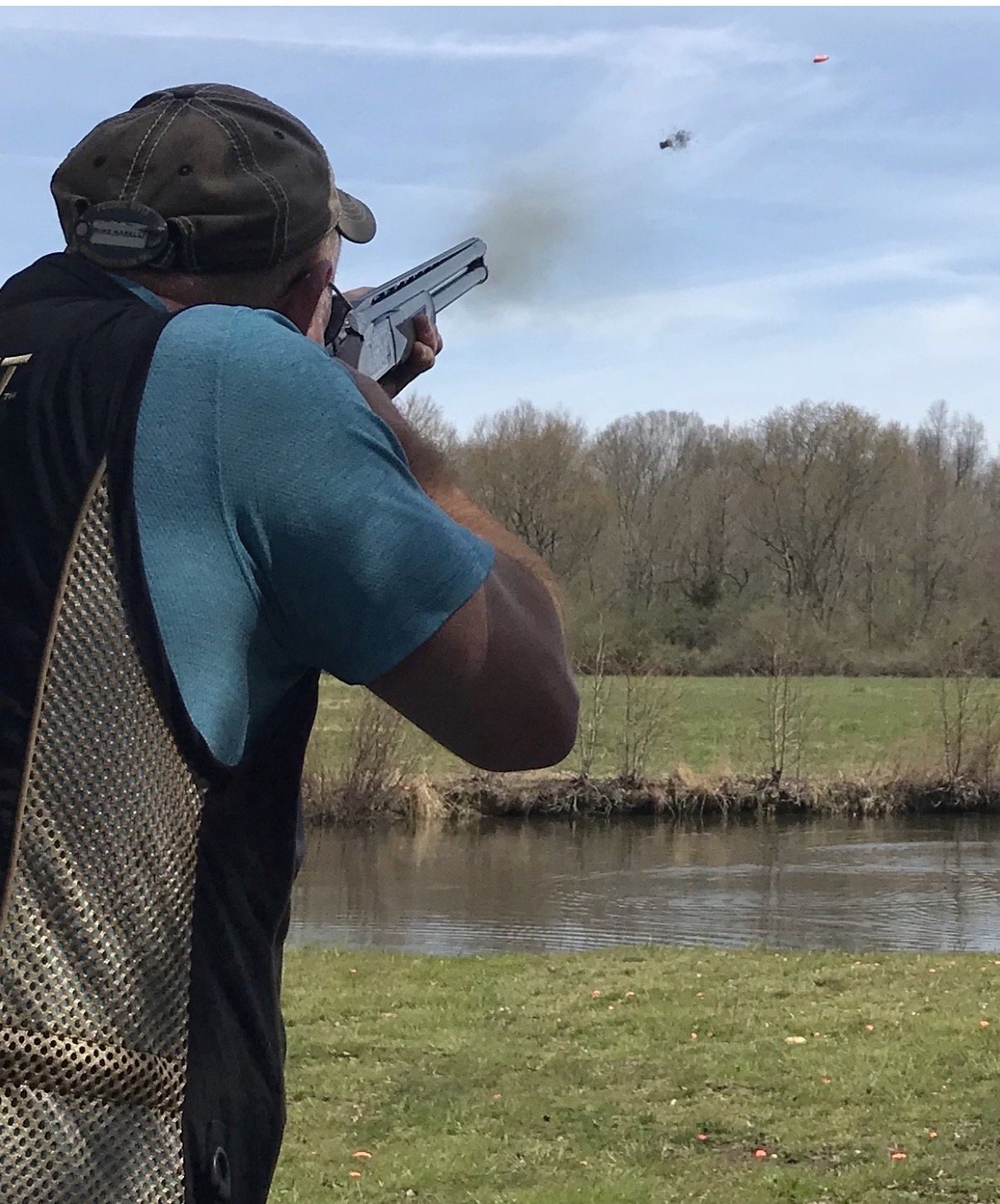 Mike Marelli shooting over water as an orange clay breaks in the sky